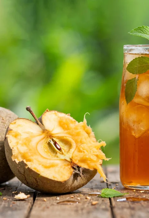 Bel sharbat recipe – amber bel sharbat with ice and mint beside a cracked wood apple